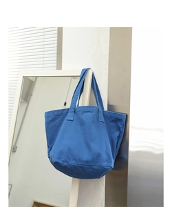 Detail showing blue washed canvas tote bag texture and spacious casual design in soft light