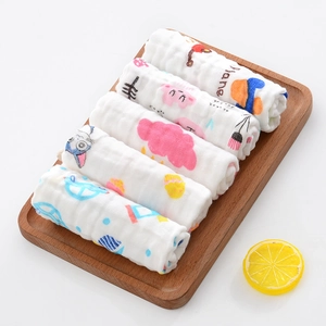 Detail of five rolled six-layer cotton muslin baby washcloths with cartoon prints on wood tray