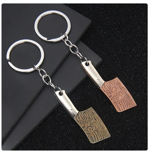 Nahaufnahme von Mini-Hackmesser-Schlüsselanhängern in Messing und Bronze mit Holzmaserung