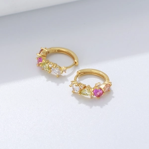 Close-up of gold huggie earrings featuring multi-colored pear and round cut zircons