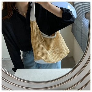 Mirror selfie showing the woven straw shoulder bag in beige with white leather straps