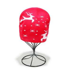 Close-up of red knit Christmas beanie featuring white reindeer and snowflake patterns