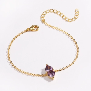 Close-up of golden chain bracelet featuring two purple teardrop-shaped gemstones