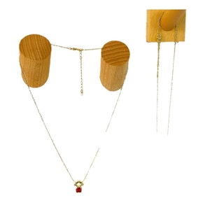 Minimalist golden necklace with a red bear pendant displayed on a wooden stand