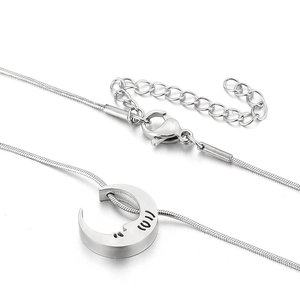 Macro detail of crescent moon pendant on a silver snake chain with lobster clasp