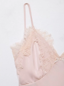 Détail d'une robe en satin rose avec bordure en dentelle de cils et petit nœud déco