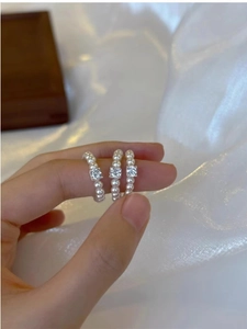 Detailed view of three vintage pearl rings with square zircon accents on fingers