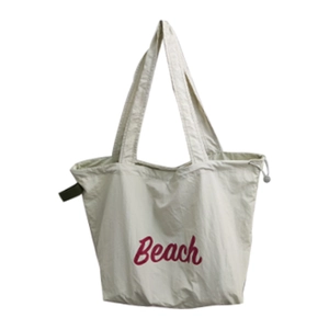 Minimalist beige drawstring tote bag with red Beach lettering and dual top handles