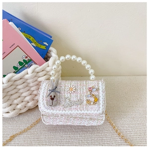 Detail of pink tweed girl's handbag with pearl handle and ornate floral charms