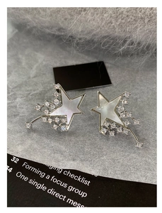Macro shot of star-shaped earrings with mother-of-pearl inlay and sparkling cubic zirconia