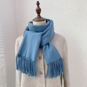 Detail of blue faux cashmere scarf with tassels draped on a wooden mannequin