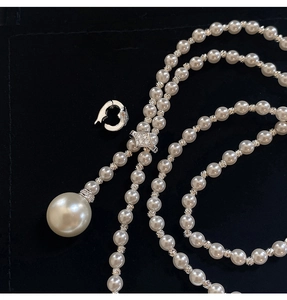 Detail of elegant pearl necklace with large drop pendant on black velvet surface