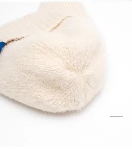 Vue détaillée des coutures renforcées et de la texture douce du haut du bonnet en maille