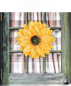 Macro detail of the layered sunflower door wreath made of yellow mesh fabric and green leaves