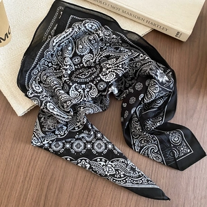 Detail showing vintage black and white paisley silk scarf on a cozy wooden cafe table