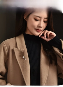 Close-up of a silver snake-shaped zircon brooch styled on a beige cashmere wool coat