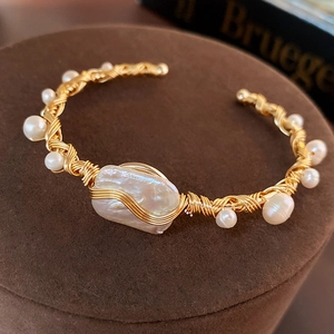 Detail of handcrafted gold wrapped wire bracelet with large baroque pearl and small pearls