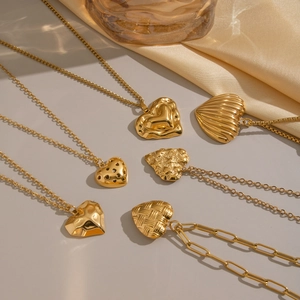 Divers colliers pendentifs coeur dorés sur tissu en soie avec reflets de verre