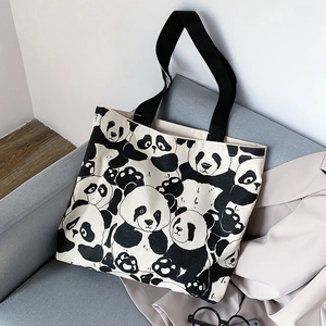 Detail shot of panda canvas tote bag with black straps resting on a grey fabric sofa