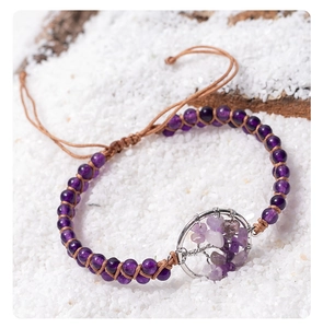 Detail of purple stone beaded bracelet with tree of life wire-wrapped charm on white sand