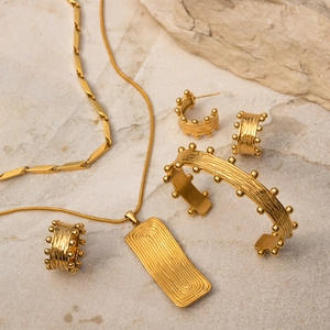 Elegant gold jewelry set with necklace and bracelet featuring textured woodgrain lines