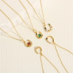 Macro detail of U-shaped gold necklaces with colorful zircon stones on textured background
