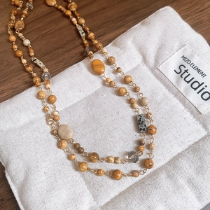 Detail of beaded gold necklace with natural stones on a vintage burlap jewelry bag
