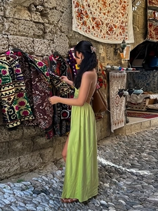 Grass green backless halter neck satin maxi dress in a scenic Mediterranean street view