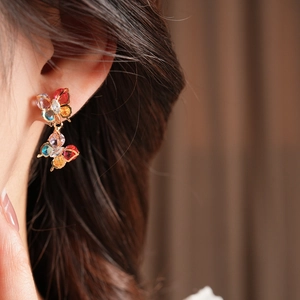 Close-up of vintage butterfly earrings with multicolored zircons on a model