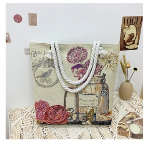 Detail of vintage canvas tote with floral bird print and woven rope handles on lace