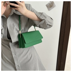 Detail of green woven PU leather shoulder bag with fine texture and golden metal buckle