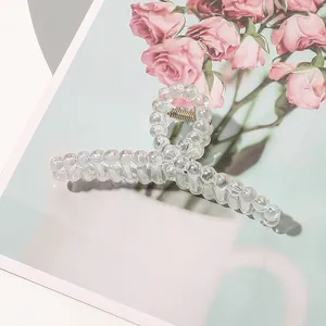 Detail of aurora bubble hair claw clip with golden metal spring on floral background