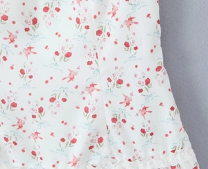Detalle de tela con estampado floral y borde de encaje en un vestido blanco de verano