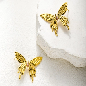 Detail of gold butterfly earrings with pink marquise gemstone on white stone