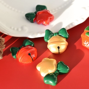 Detail of red and gold Christmas bell and star resin charms with green bows for DIY crafts