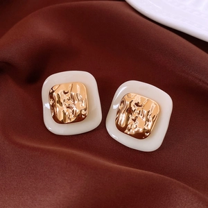 Makroaufnahme von Retro-Essigsäure-Ohrringen mit gehämmerter Goldplatte und Silberstiften
