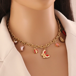 Detail of gold beaded necklace featuring ladybug, butterfly, and chili pepper charms