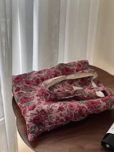 Détail du sac cabas en jacquard rose avec motif de roses rouges sur table en bois