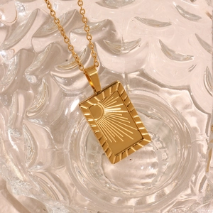Macro shot of 18K gold plated sunburst pendant with vintage tarot rectangular design