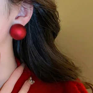 Glossy red spherical pearl drop earrings in minimalist style worn by model