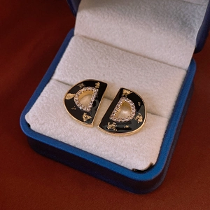 Macro view of vintage style D-shaped gold earrings with black enamel and crystals