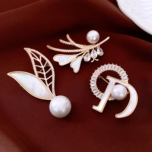 Macro shot of 14K gold plated pearl and crystal brooches on dark velvet background