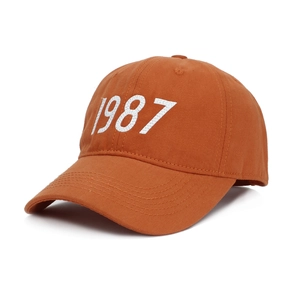 Detail of caramel cotton baseball cap with white 1987 embroidery and reinforced stitching
