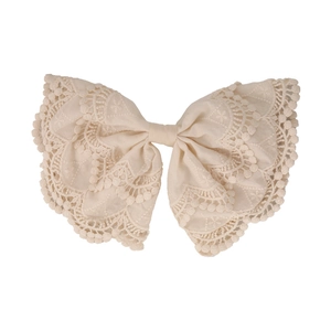 Elegant beige lace hair clip with embroidery and pom-pom trim on a white background