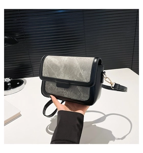 Detail view of small square crossbody bag showing black and grey contrast stitching