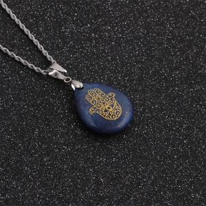 Macro shot of blue lapis lazuli drop pendant with gold Hand of Fatima on silver twist chain
