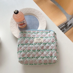 Quilted floral makeup bag detail showing fresh tulip pattern and zip closure on desk
