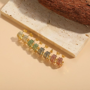 Close-up of multi-layer C-shaped gold earrings with colorful cubic zirconia stones