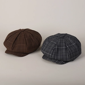 Detail of plaid newsboy hats in brown and black-white check with thick textured fabric