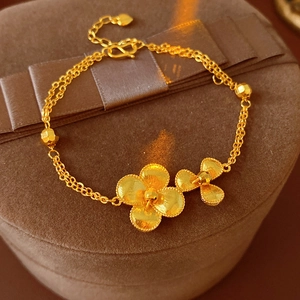 Detail of vintage gold plated flower bracelet with matte texture and dual chain